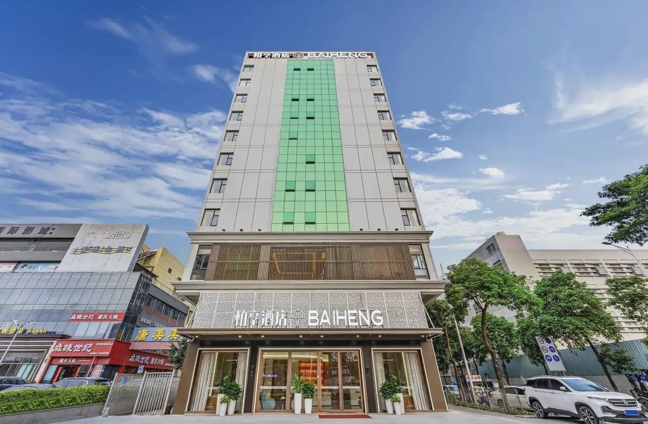 Een hoog gebouw met een groene gevel en de naam "BAIHENG" op de begane grond.