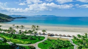 A beach resort with palm trees, a pathway, and beach huts. - Azure Beach Hotel (Da Nang)