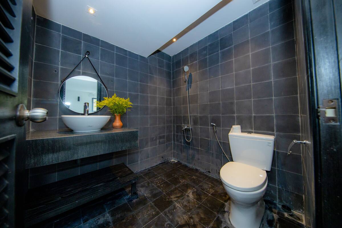 A modern bathroom with a white toilet, a sink with a bowl, a mirror, and a shower.