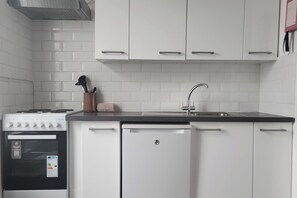 A compact kitchen with white cabinets, a stove, and a dishwasher.