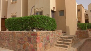 A multi-story building with stone steps leading to the entrance, surrounded by well-maintained bushes.