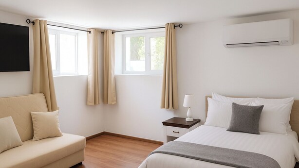 Ein modernes Hotelzimmer mit Bett, Schlafsofa, Nachttisch und Klimaanlage.