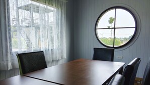 Ein Zimmer mit einem Rundfenster, einem Tisch und zwei Stühlen.