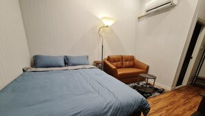 Ein Schlafzimmer mit einem großen Bett, einem braunen Ledersessel, einem kleinen Tisch und einer Stehlampe.