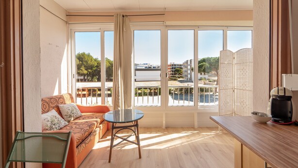 A balcony with a sofa, a table, and a chair. - WELCS ESTUDIO 212 EMP cerca del mar (Rosas / Roses)