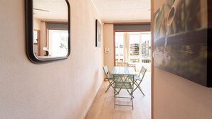 A hallway with a dining area featuring a table and chairs, a mirror, and a painting of a water scene. - WELCS ESTUDIO 212 EMP cerca del mar (Rosas / Roses)