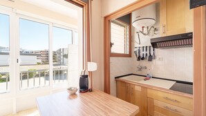 A kitchen with wooden cabinets, a sink, and a window overlooking a cityscape. - WELCS ESTUDIO 212 EMP cerca del mar (Rosas / Roses)