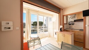 A modern kitchen with a dining area, a balcony with a view, and a small table. - WELCS ESTUDIO 212 EMP cerca del mar (Rosas / Roses)