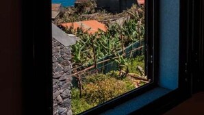 A window with a view of a coastal landscape, including a body of water and distant mountains. - GuestReady - Magical refuge in Madeira (Seixal)