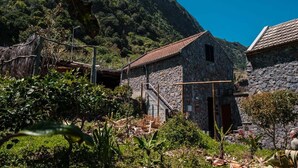 A stone building with a tiled roof, surrounded by lush greenery and a mountainous backdrop. - GuestReady - Magical refuge in Madeira (Seixal)