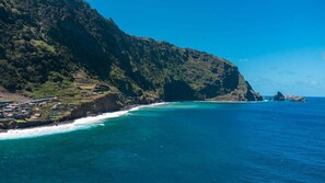 A coastal landscape with terraced fields and a clear view of the ocean. - GuestReady - Magical refuge in Madeira (Seixal)