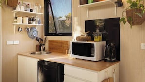 Cocina compacta con microondas, lavabo y ventana con vistas a un jardín.