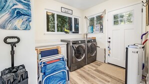 A laundry room with a washing machine, dryer, and a cart with folded clothes. - Redwood Home - view of the river! (Ben Lomond)