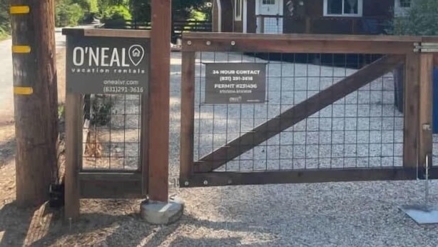 A gated entrance with a wooden gate, a sign for O'Neal Vacation Rentals, and a contact number. - Redwood Home - view of the river! (Ben Lomond)