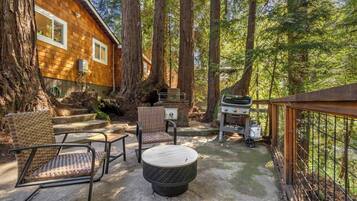 An outdoor patio with wicker furniture, a grill, and a wooden deck.