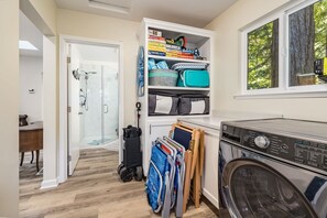 A laundry area with a washing machine, a drying rack, and a shelf with board games. - Redwood Home - view of the river! (Ben Lomond)