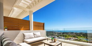 Un balcon avec un canapé, une table en bois et une vue sur le paysage.