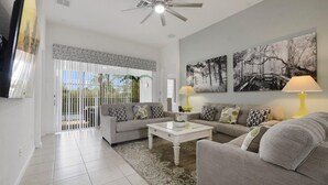 A living room with a sofa set, a coffee table, and a TV. There are two lamps on side tables.