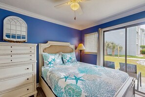 Classic bedroom with a bed, dresser, and mirror, offering a view of the outside through large windows.