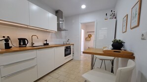 A modern kitchen with white cabinets, a wooden countertop, a built-in oven, and a small dining area with a white chair and table. - Ref: 324 Centric 3 bedroom apartment with swimming pool and close to everything (Fuengirola)