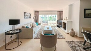 Un salon moderne avec un canapé, une table basse, un téléviseur et une cheminée.