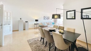 Un salon moderne avec un coin repas, comprenant un ensemble de canapés, une table basse et un lampadaire.