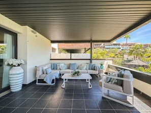 A modern outdoor living area with a sofa set, a coffee table, and a seating area with cushions. - Hoyo 3 | Marbella Resort Golf Pools Apartment (Benahavís)