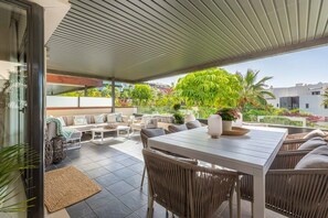 An outdoor patio area with a dining table, chairs, and a sofa set.