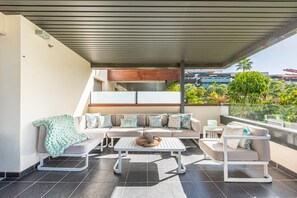 A modern outdoor living area with a sofa, a coffee table, and a dining table. - Hoyo 3 | Marbella Resort Golf Pools Apartment (Benahavís)