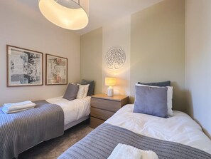 A hotel room with two beds, a bedside table with a lamp, and artwork on the wall. - Hoyo 3 | Marbella Resort Golf Pools Apartment (Benahavís)