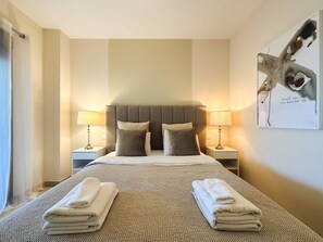 A hotel room with a large bed, two bedside tables, and a wall-mounted artwork.