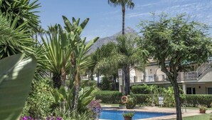 A pool surrounded by tropical plants and a building with balconies. - Las Brisas | Penthouse Rooftop Terrace Pool Family Only (Marbella)