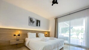 A modern hotel room with a large bed, two bedside tables with lamps, a wooden headboard, and a large window with a view of the outdoors. - Las Brisas | Penthouse Rooftop Terrace Pool Family Only (Marbella)