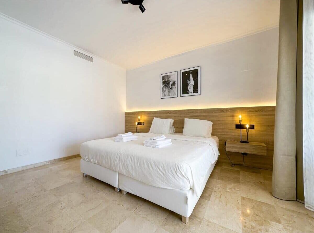 Ein modernes Hotelzimmer mit einem großen Bett, zwei Nachttischen und einem Holzkopfteil.