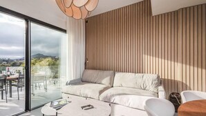Un saló modern amb un sofà seccional, una taula de menjador de vidre i vista cap a l'exterior.