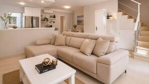 Een moderne woonkamer met een beige hoekbank, een witte salontafel en een trap.