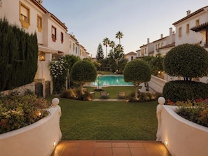 A pool area with a clear view of the pool, surrounded by well-maintained hedges and a neatly trimmed lawn.