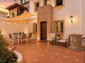 A courtyard with a dining area, outdoor seating, a decorative stone table, and a brick wall.