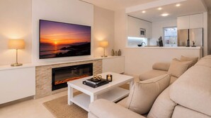 Een moderne woonkamer met een open haard, een flatscreen televisie en een bank.