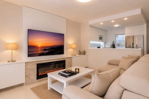 A modern living room with a fireplace, a flat-screen TV, and a sofa.