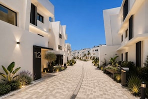 Ein moderner Hotelgang mit weißen Gebäuden, nummerierten Türen und gut beleuchteten Wegen.