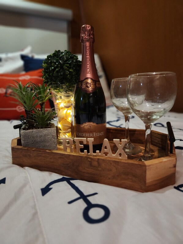 A wooden tray with a bottle of Roederer Estate Brut Rosé Champagne, two wine glasses, a small potted plant, and a decorative sign spelling "RELAX".