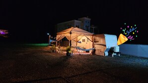 A caravan with a tent-like structure, a hammock, and a small table with chairs. - Camper Capacidad Hasta 6 Personas (Cabo Rojo)