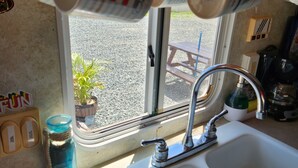 A kitchen with a sink, a window, and hanging mugs. - Camper Capacidad Hasta 6 Personas (Cabo Rojo)