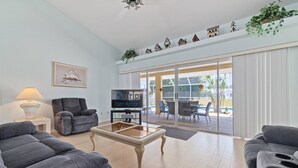 Una sala de estar con un sofá, un sillón y un televisor sobre un mueble.
