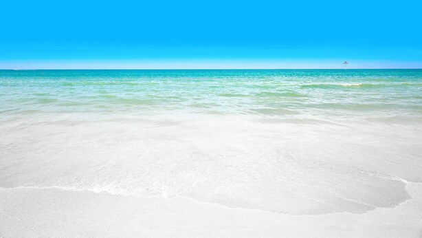 Una playa con agua turquesa cristalina y una orilla arenosa.