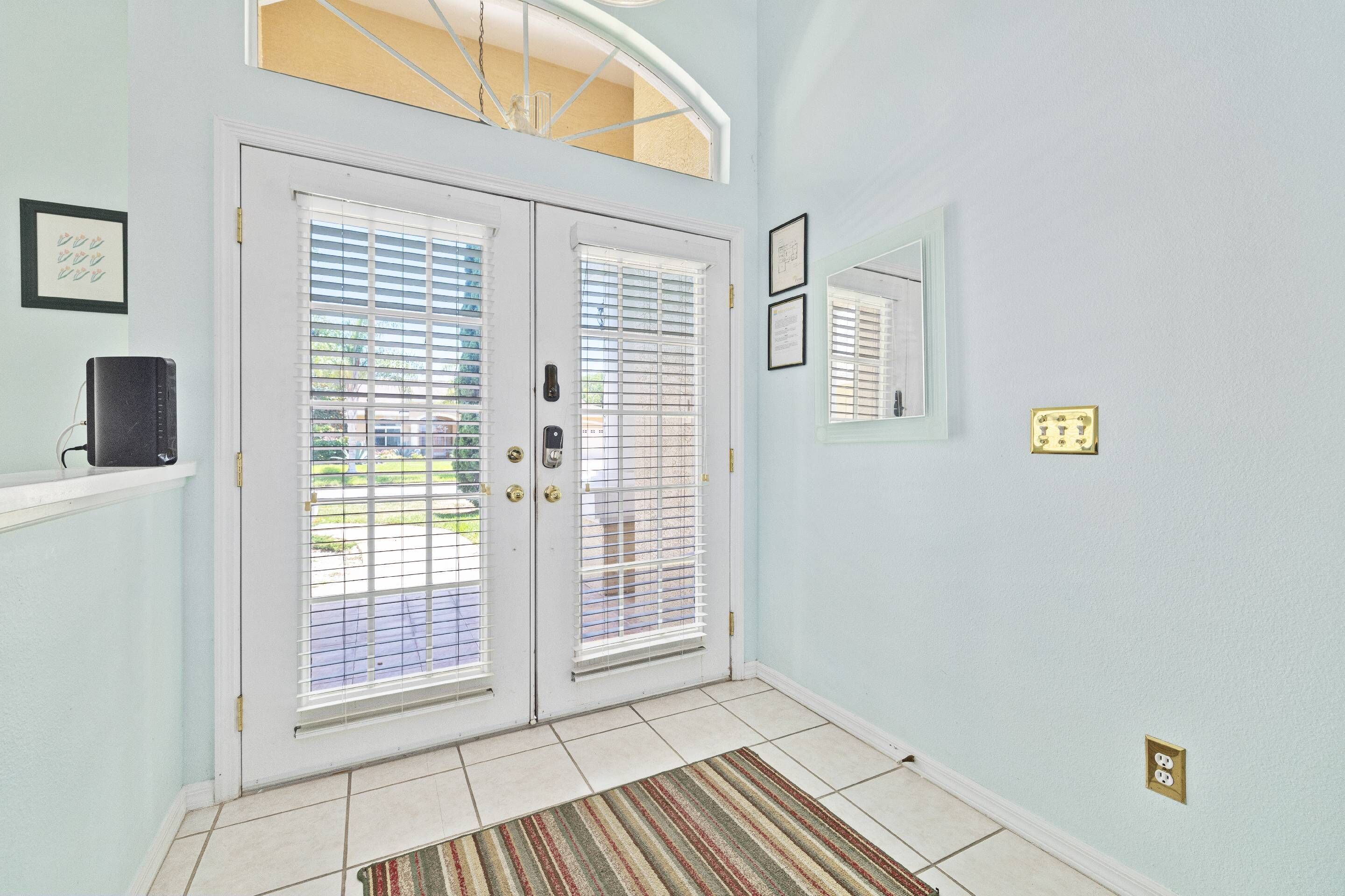 A hallway with a double door, a small rug, and a framed picture on the wall.