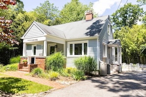 A single-story house with a brick foundation, white siding, and a grey roof.