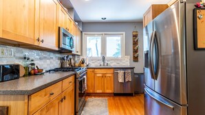 A modern kitchen with wooden cabinets, stainless steel appliances, and a large refrigerator. - Mins to Downtown in Waterfront community at Pet-Friendly Pinecrest Bungalow (Annapolis)