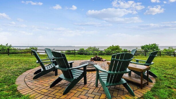 A circular outdoor seating area with green Adirondack chairs and a brick fire pit. - Mins to Downtown in Waterfront community at Pet-Friendly Pinecrest Bungalow (Annapolis)